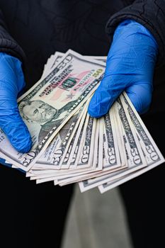 Photo by Michal Dziekonski Hands in protective gloves holding multiple US dollar bills, symbolizing virus protection and financial transactions.