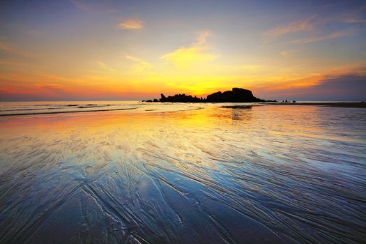 A serene sunset over a reflective ocean shoreline with vibrant colors.