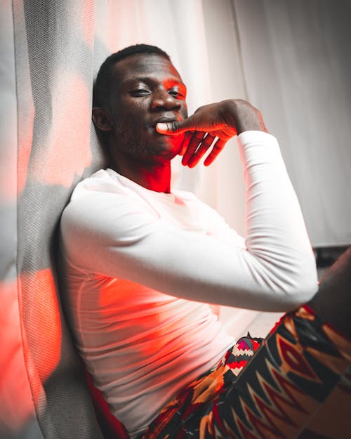 Black man sitting under red light