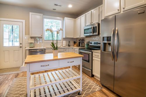 Free Spacious kitchen featuring stainless steel appliances and island with wooden countertop. Stock Photo