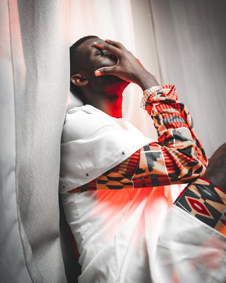 African Man With Closed Eyes Sitting Near Curtain