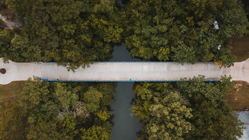 Drone view concrete bridge connecting lush river coasts covered with green abundant trees