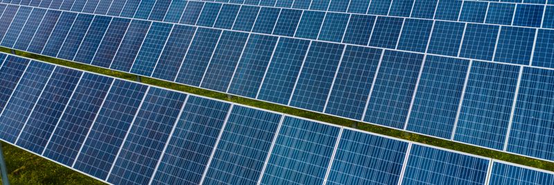 High angle pole mounted solar energy trackers installed on green field in solar power station