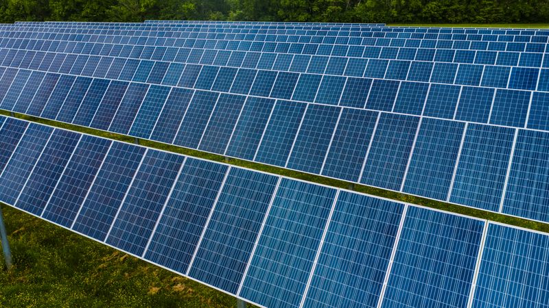 High angle pole mounted solar energy trackers installed on green field in solar power station
