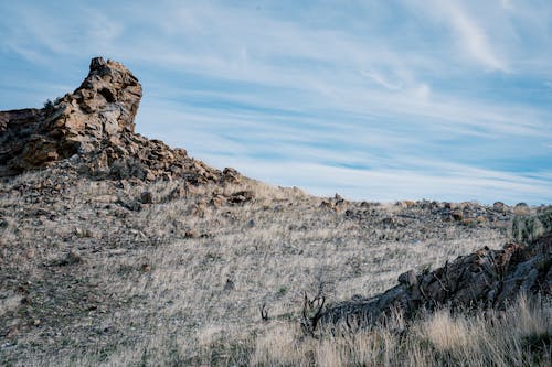 Rough hill peak with dry random vegetation against clear blue sky in mountainous terrain