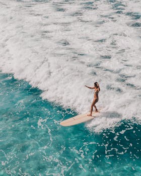 这是一张令人惊叹的航拍照片：一名冲浪者正熟练地在夏威夷清澈的蓝色海水中冲浪
