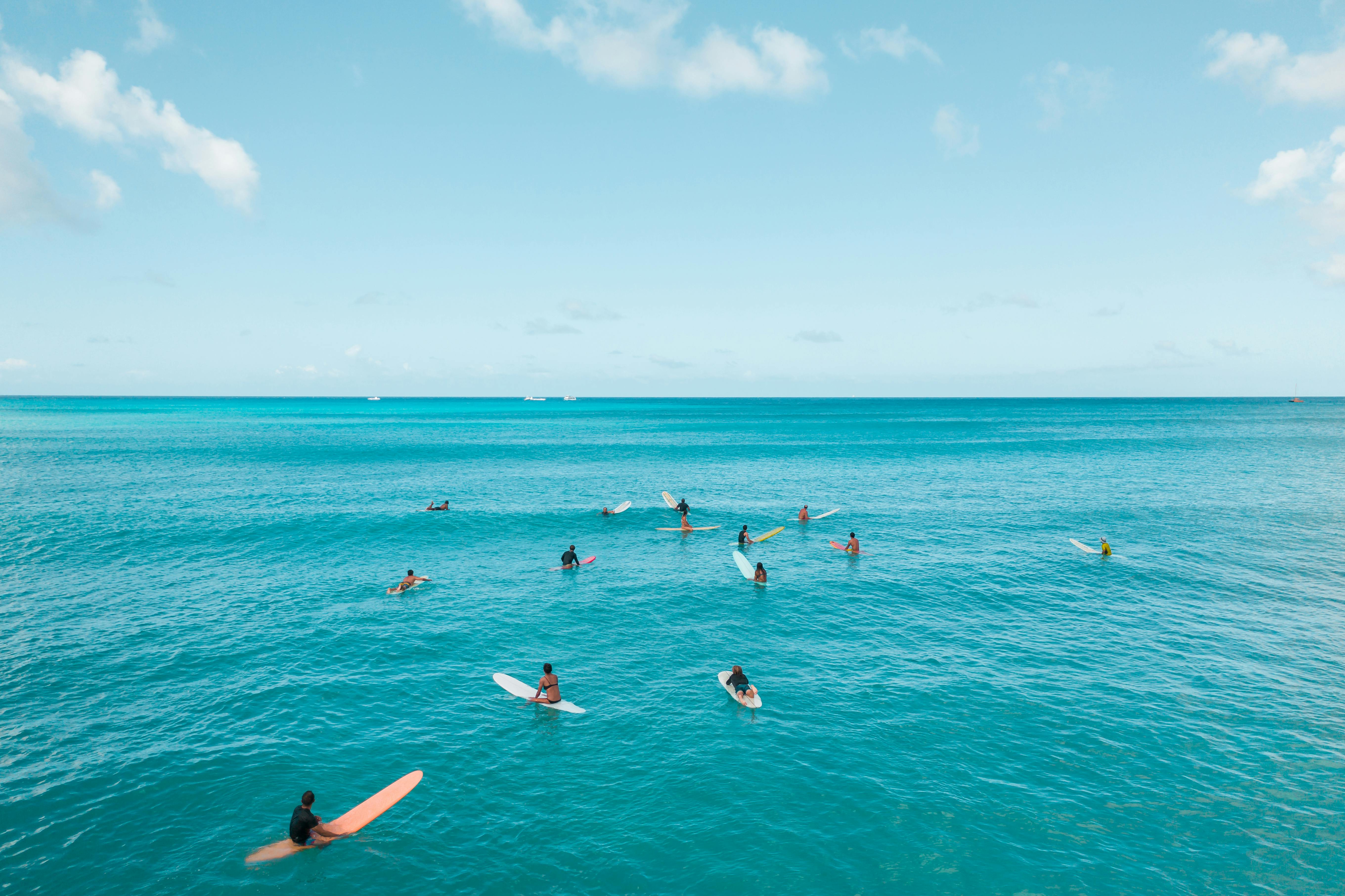 在晴朗的天空下，一群冲浪者骑着彩色冲浪板，享受着檀香山碧绿的海水