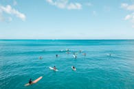 在晴朗的天空下，一群冲浪者骑着彩色冲浪板，享受着檀香山碧绿的海水