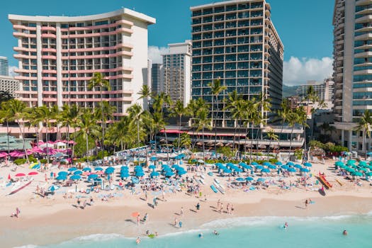 Aerial shot of Waikiki's bustling beach with colorful umbrellas and hotels, perfect summer vacation vibe.