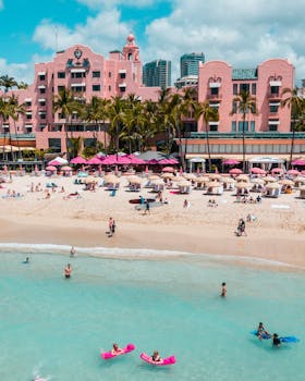 Photo by Jess Loiterton Aerial view of Waikiki Beach with iconic pink hotel, palm trees, and ocean.