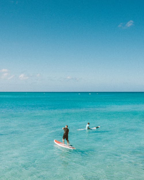 Woman in Blue Bikini Riding White Surfboard on Blue Sea