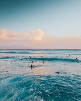 Surfers riding waves at sunset in Hawaii, capturing the ocean's beauty and vibrant island life.