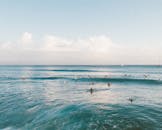 冲浪者在蓝天下在夏威夷晶莹剔透的海洋中享受海浪的鸟瞰图