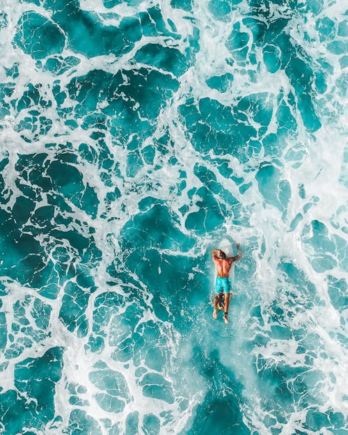 Woman in Blue and White Bikini Swimming on Water