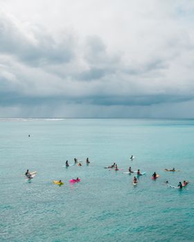 一群夏威夷的冲浪者在多云的天空下等待海浪