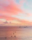 夏威夷海滩的日落宁静祥和，色彩柔和的大海上，冲浪者和船只点缀其间