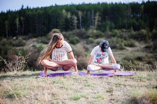 A mother and child practicing yoga on grassy field amidst nature, emphasizing wellness and bonding.