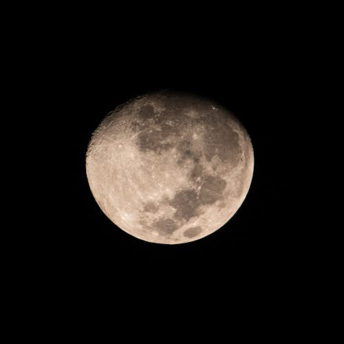 Illustration of bright glowing moon in waxing gibbous phase on plain black background