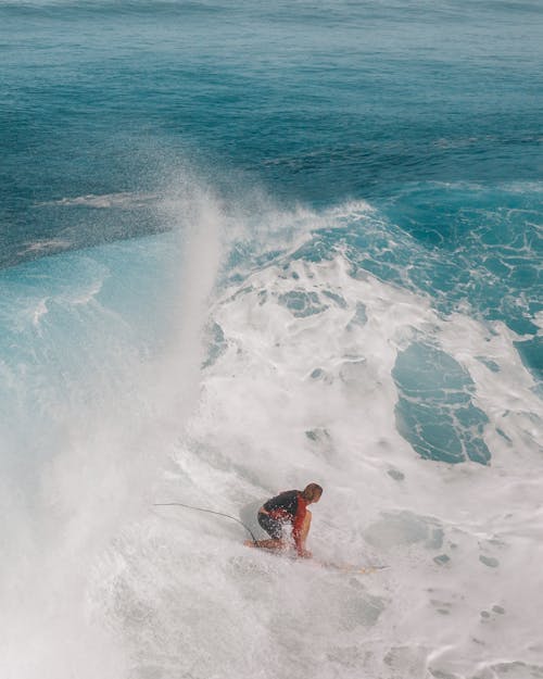 A Person Meeting the Waves of the Sea while Riding on a Surfboard