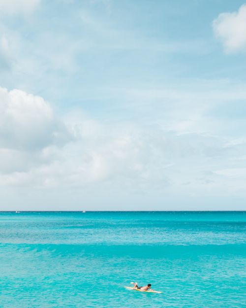 Free A serene image of a lone surfer on a turquoise sea under a bright sky in Honolulu, Hawaii. Stock Photo