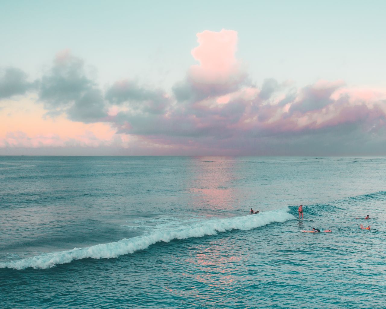 peaceful sunset scene with surfers catching waves on a hawaiian beach
