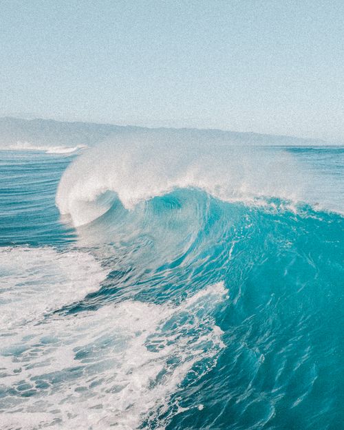 Free A powerful ocean wave crashes with white foam against a clear blue sky. Stock Photo