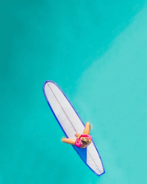 Man in Blue and White Board Shorts Riding White and Blue Surfboard