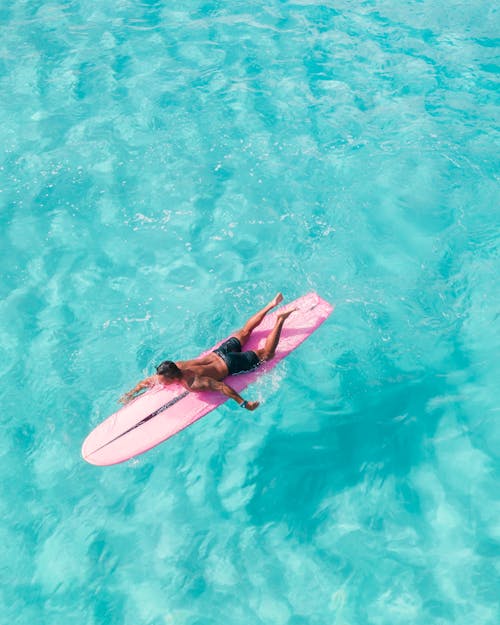 Woman in Pink Bikini Lying on Pink Surfboard on Water