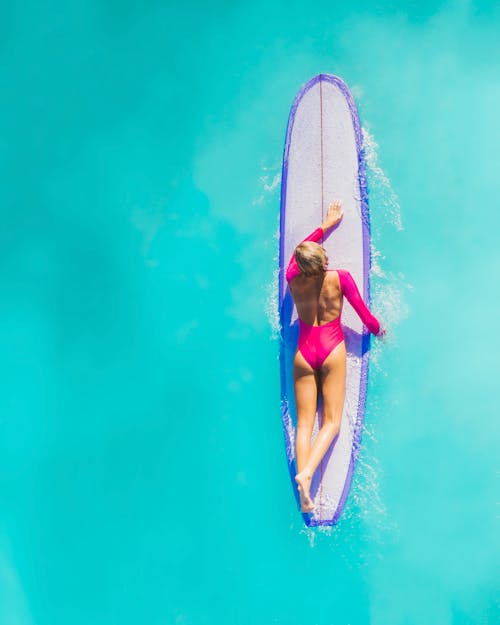 Woman in Pink Bikini Lying on Blue Surfboard