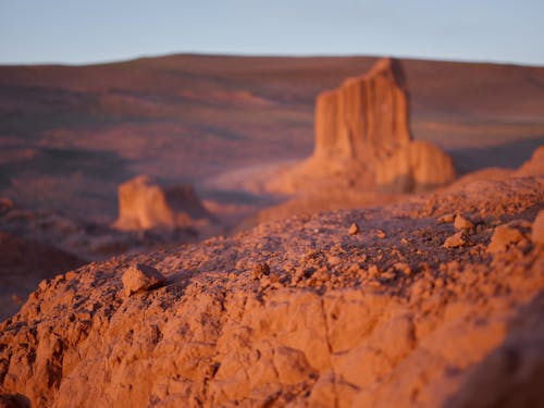 From above of red rough sand on edge of mountain on blurred background of rocky desert terrain with cliffs under clear blue sky