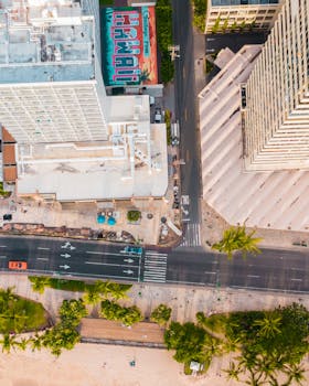 Photo by Jess Loiterton Stunning aerial view of urban Waikiki, Hawaii with vibrant street and buildings.