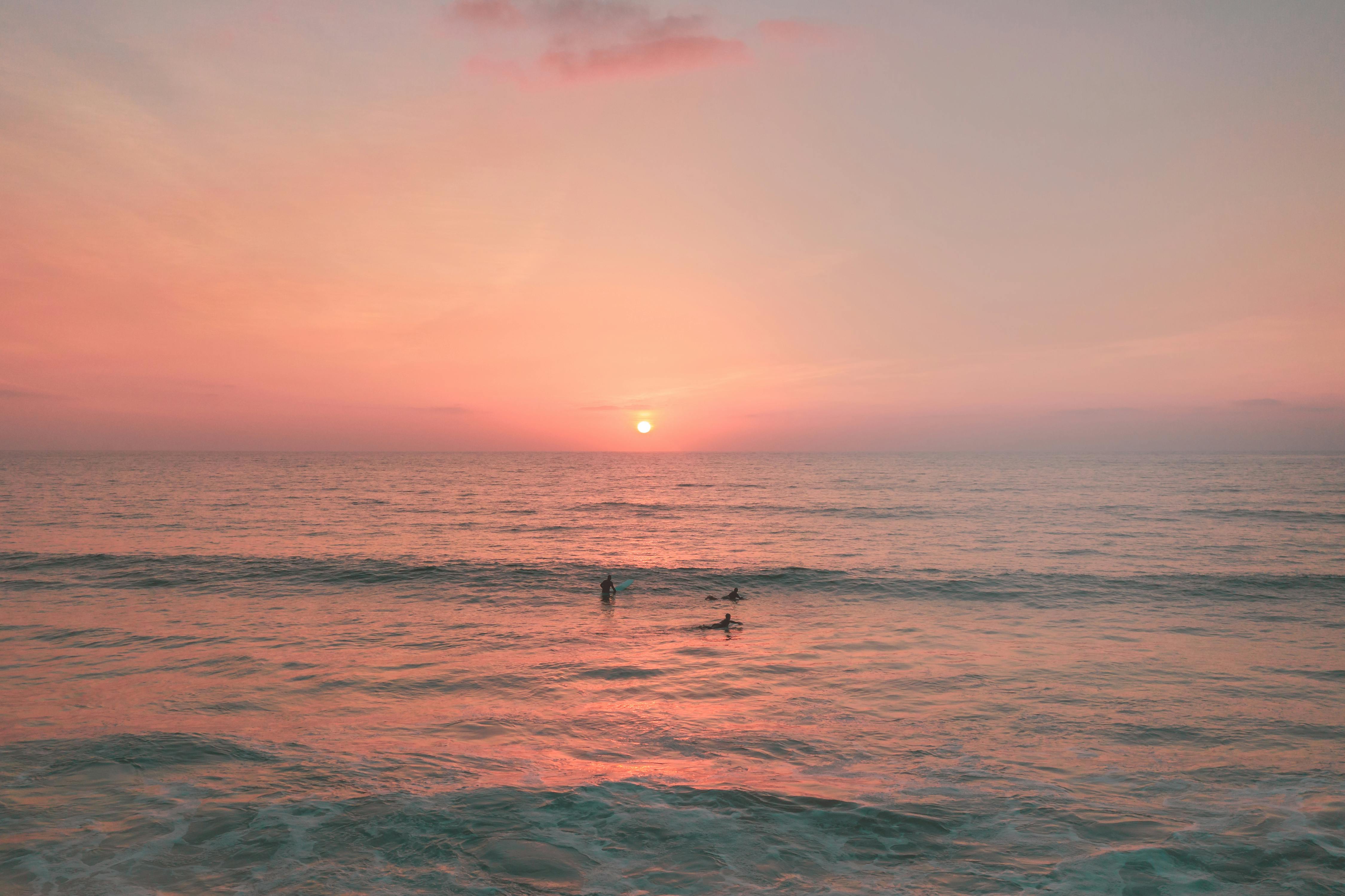 夏威夷海洋上超现实的日落，冲浪者享受着充满活力的海浪