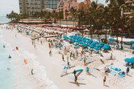 夏威夷威基基海滨的航拍照片生动地展示了夏日天空下日光浴者和绿松石伞的景象