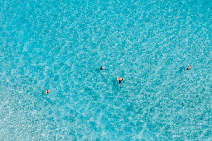 Luftaufnahme von Menschen, die in kristallklarem hawaiianischem Meerwasser schwimmen. Perfekte Urlaubsszene.