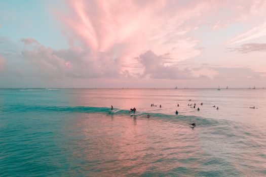 Surfers enjoying the waves at sunset on Waikiki Beach, Hawaii.