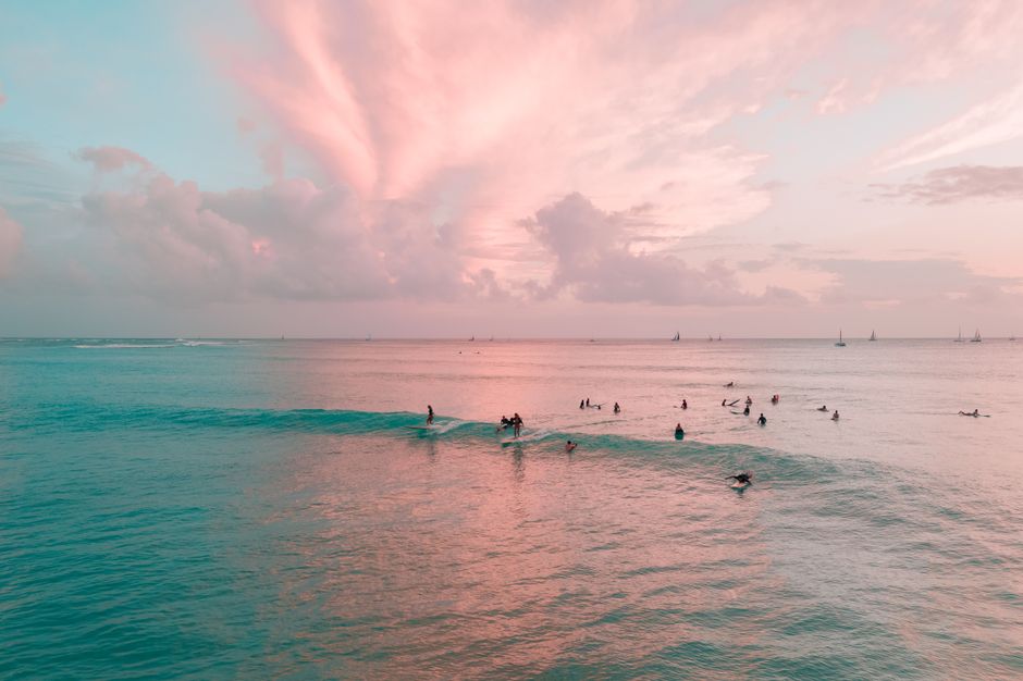 Surfers enjoying the waves at sunset on Waikiki Beach, Hawaii.