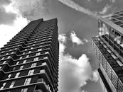 一张引人注目的黑白照片以低角度拍摄，展现了多云天空下的城市摩天大楼