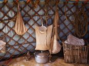 Inner part of authentic ger of Mongolian nomads with household utensils and fabric bags for storage near wooden frame of house under tent