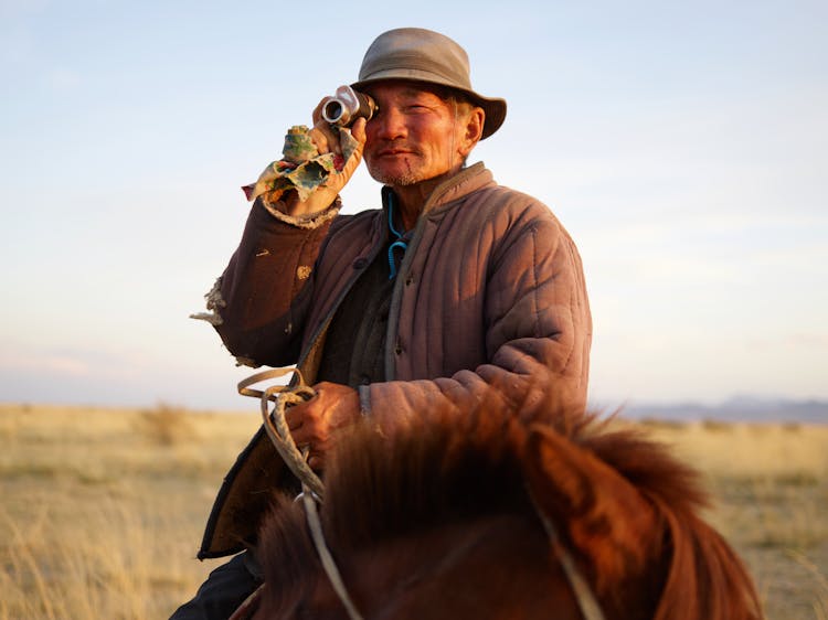 Satisfied Senior Mongolian Horseman With Monocular In Steppe