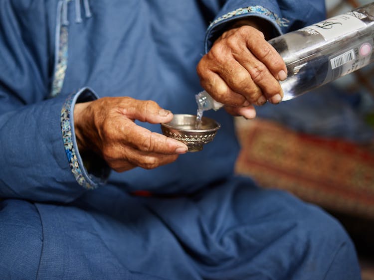 Crop Old Man Pouring Vodka In Resonance Bowl