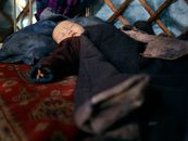 一个穿着温暖民族服装的亚洲婴儿，正躺在地毯上，盖着毯子睡觉