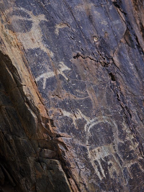 Free From above of shabby ancient drawings of animals on cracked surface of stone cave Stock Photo