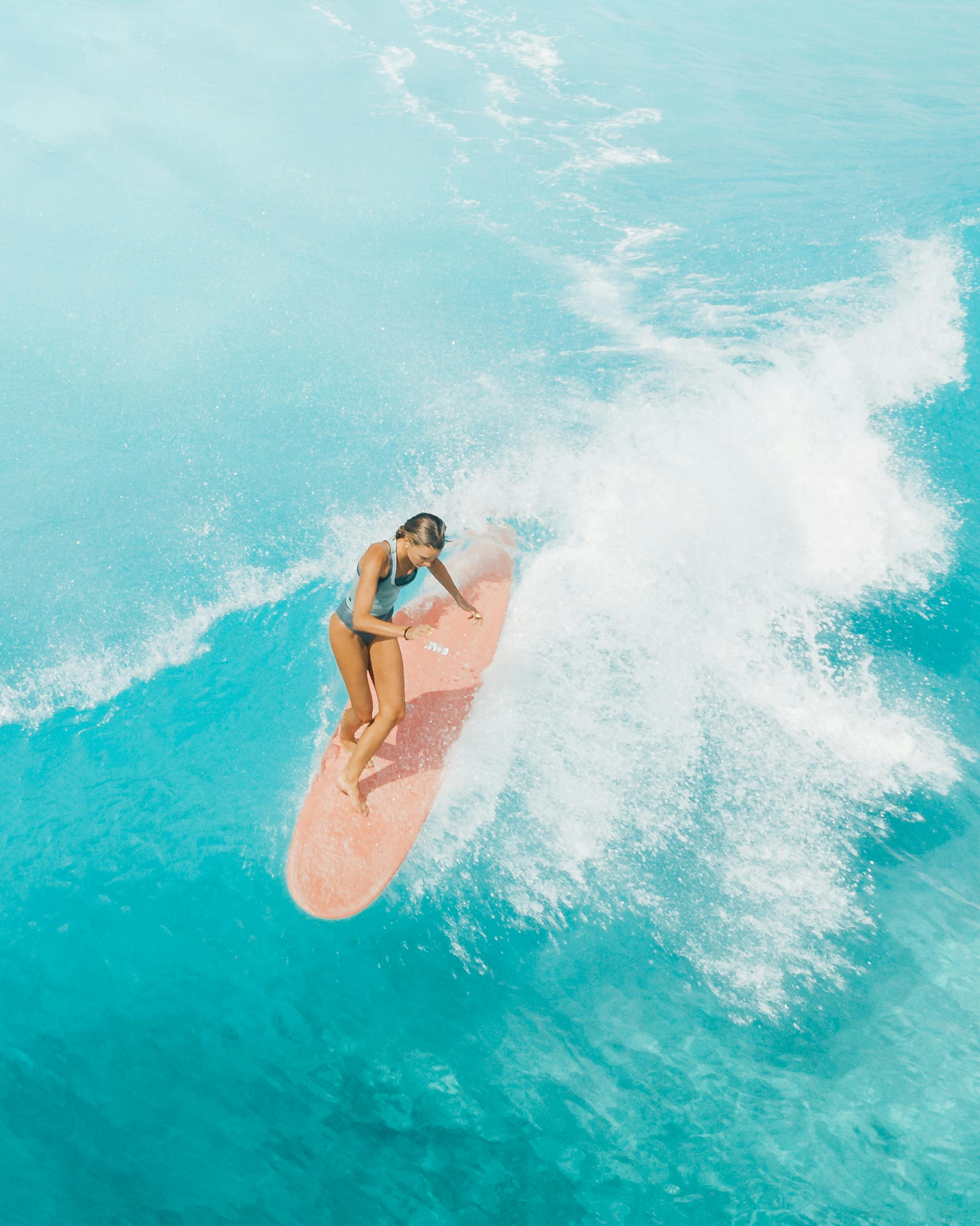 woman in pink bikini surfing on water