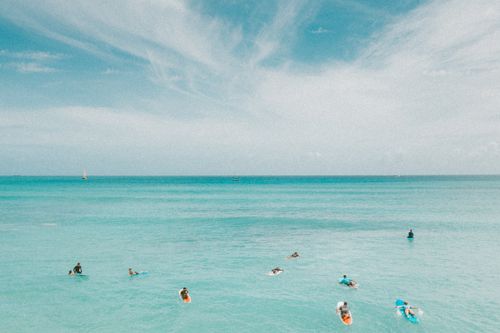 Free Aerial view of surfers on turquoise ocean waves in Hawaii with clear skies. Stock Photo