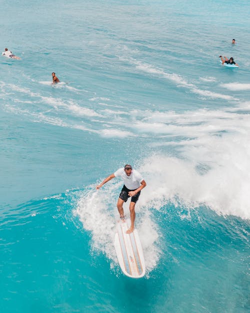 Man in Blue Shorts Surfing on Sea