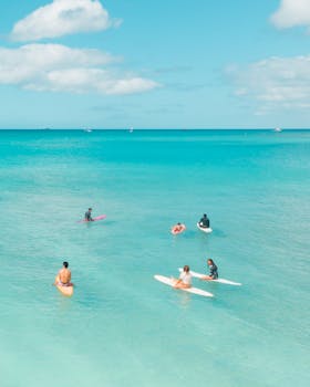 Surfers enjoying a sunny day on clear blue ocean waters, a perfect summer paradise.