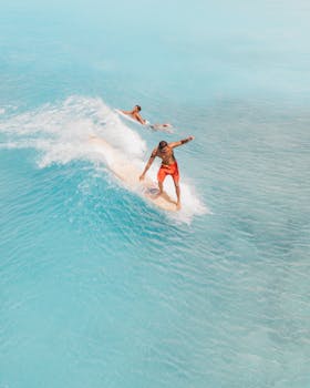 Aerial shot of surfers catching waves in the clear blue waters of Honolulu, Hawaii.