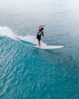 A surfer catches a wave in the clear blue ocean off the coast of Hawaii, showcasing exciting surfing action.