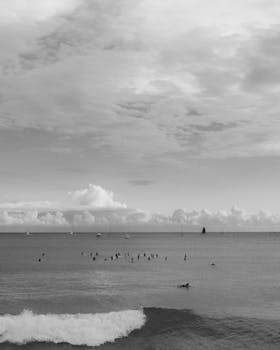 Surfers enjoy a peaceful day on the ocean in Hawaii, under dramatic skies.