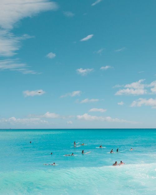 Free A stunning aerial view of surfers catching waves in the vibrant blue waters of Hawaii. Stock Photo